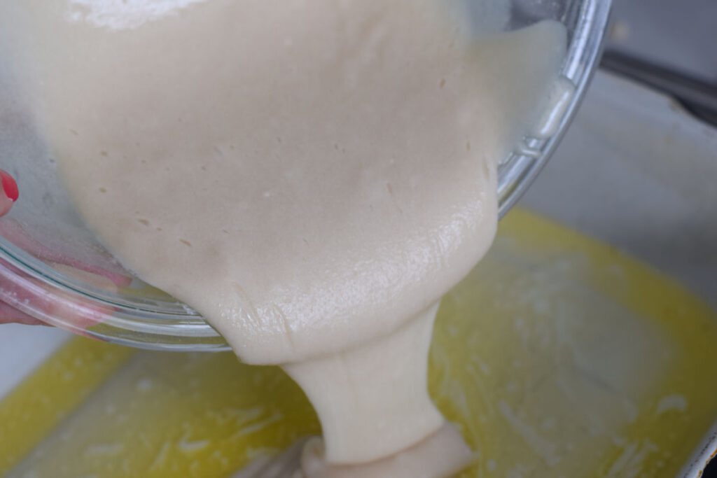 pouring batter over butter in cobbler 