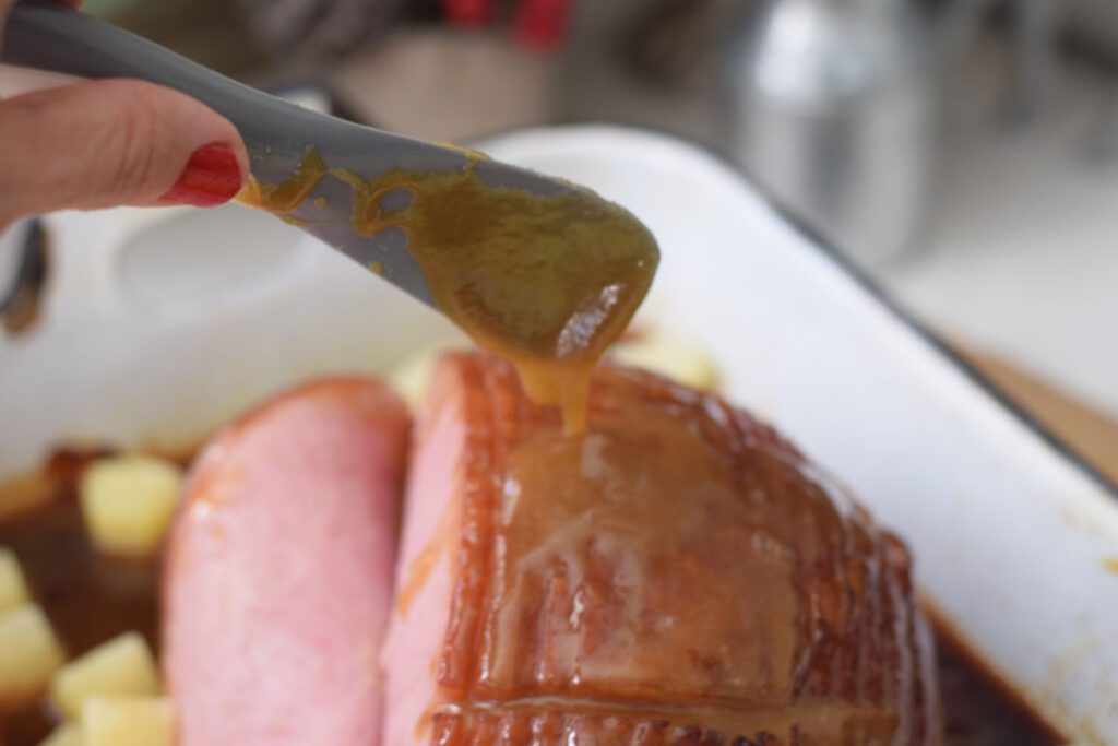 spooning honey glaze over ham 