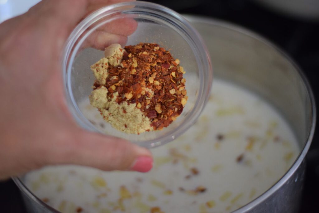 adding spices to milk mixture for spinach maria recipe